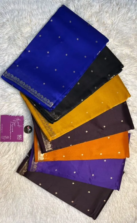 Finished sarees folded in a fan of colours — blue, black, mustard, brown and purple