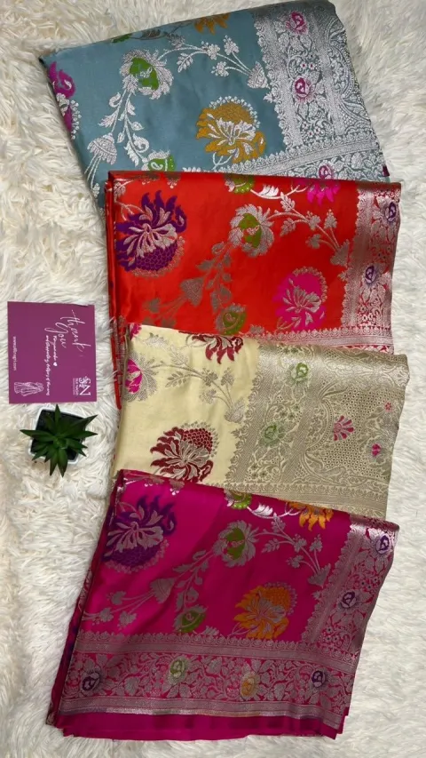 A stack of finished Banarasi sarees in several colourways with a Silk Nagri thank-you card