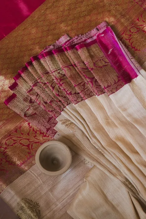 Close-up of a saree with an ivory body and a magenta and gold zari pallu